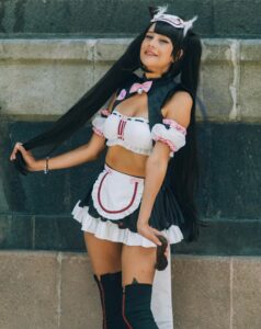 A woman in a detailed cosplay costume poses confidently outdoors, showcasing her unique outfit.